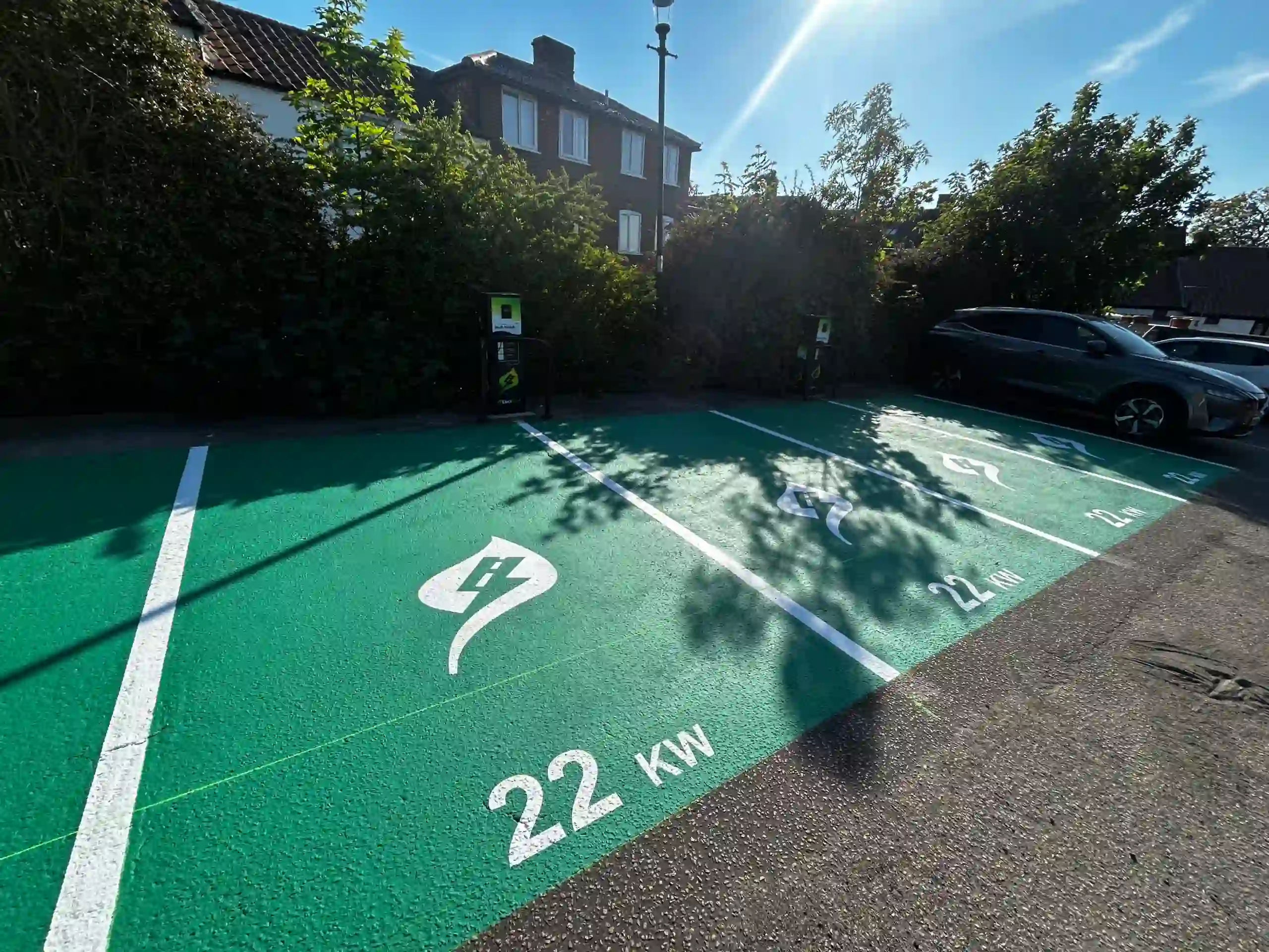 Accessible Parking Spaces A parking lot with several electric vehicle charging bays painted bright green, featuring white EV symbols and "22 KW" text on the ground