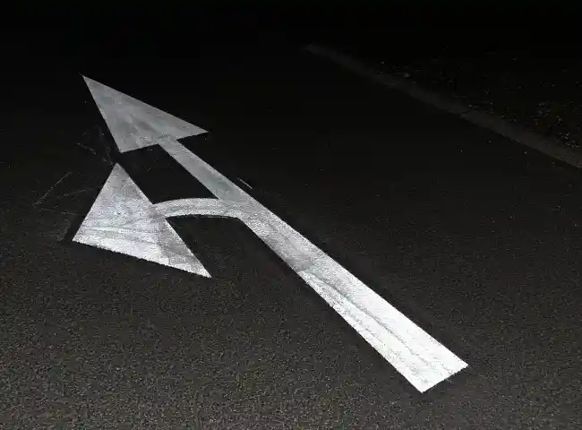 white road marking arrow on dark asphalt by car park line marking company